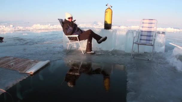 Divers are submerged under water in ice hole of lake Baikal. — Stock Video