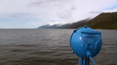 Karanlık gökyüzünün arka planında su yüzeyinde dalgalar ve gün batımında gri bulutlar.