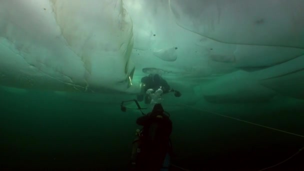 Camarógrafo submarino con cámara y buzo técnico bajo el hielo del lago Baikal. — Vídeos de Stock