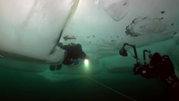 Underwater cameraman with camera and technical diver under ice of lake Baikal. — Stock Video