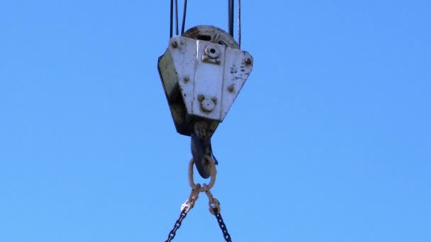 Hook of construction crane with cargo winch, hoist rope against clear blue sky. — Stock Video