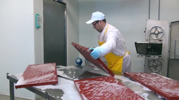 Человек-рабочий дезинфицирует стол для резки мяса в промышленном цехе. — стоковое видео