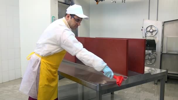 Människan tar bort vatten från bordet efter tvättning och desinfektion i verkstaden. — Stockvideo