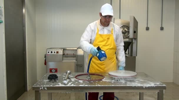 A férfi munkás fertőtleníti a kolbászkészítő gép alkatrészeit az ipari műhelyben. — Stock videók
