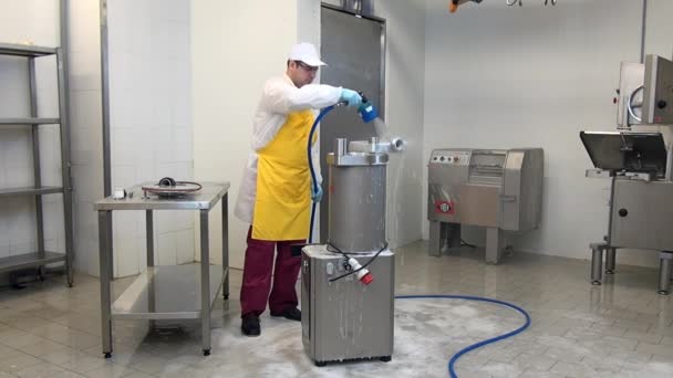 Работник стирает промышленное оборудование для производства колбас. — стоковое видео