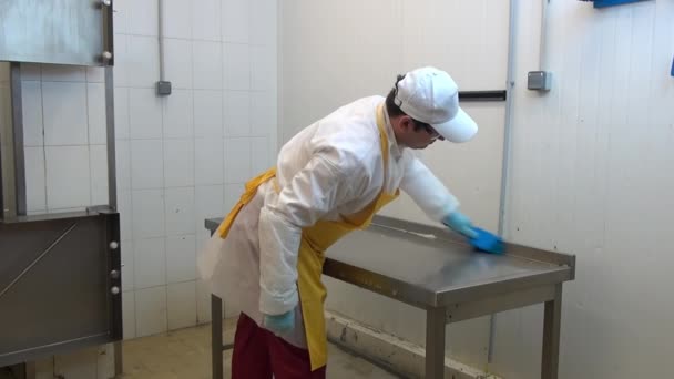 Man werknemer wast en desinfecteert tafel in industriële werkplaats. — Stockvideo