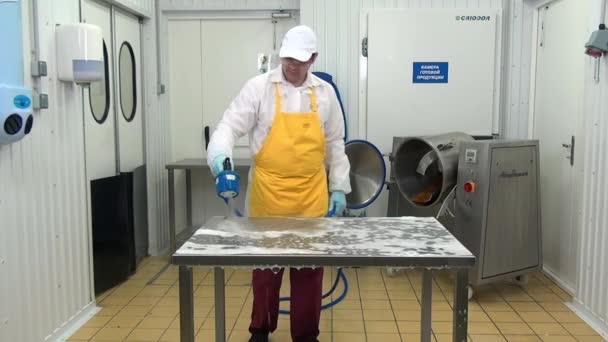 Arbeiter in der Lebensmittelproduktion wäscht und desinfiziert Tisch in Industriehalle. — Stockvideo