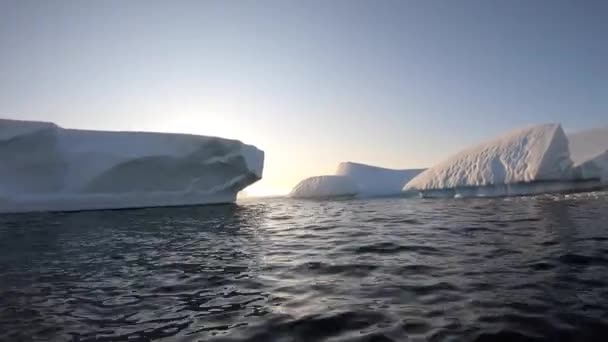 Um tiro de um barco a remos a nadar à volta de um iceberg. — Vídeo de Stock