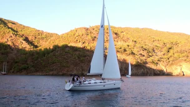 トルコの山の影と太陽の光を背景にヨットの人々. — ストック動画