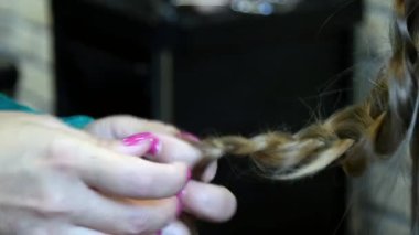 Berber dükkanındaki genç bir kız için örgü örmekten saç stili yaratma süreci.