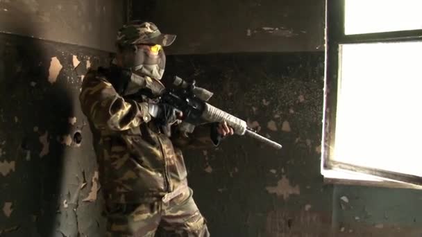 Άντρας με στρατιωτικές στολές παίζει σε ερειπωμένο κτίριο στρατιωτικού πολυγώνου. — Αρχείο Βίντεο