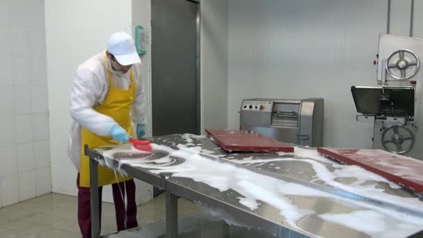 Man arbetare borstning med röd borste och skum industribord för att skära kött. — Stockvideo