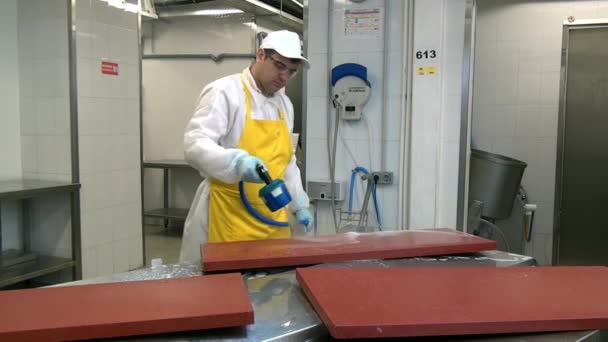 Man werknemer desinfecteert tafel voor het snijden van vlees in industriële werkplaats. — Stockvideo