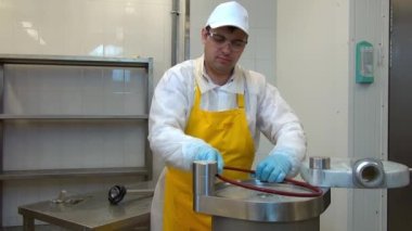 Erkek işçi, sosis parçaları üretimi için ekipmanları söküyor..