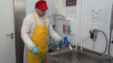 Adam atölyede dezenfektan çözeltisiyle ekipman hazırlıyor..