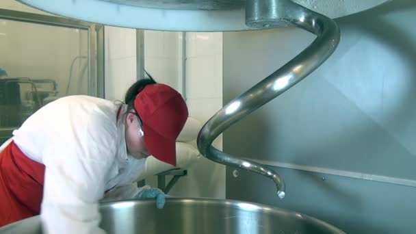 Γυναίκα με κόκκινη ποδιά και καπάκι πλένει ζυμάρι στη βιομηχανία τροφίμων. — Αρχείο Βίντεο