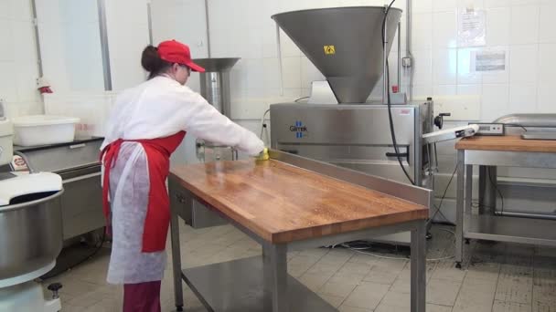 Arbeiterin desinfiziert Holztisch in Industriehalle. — Stockvideo