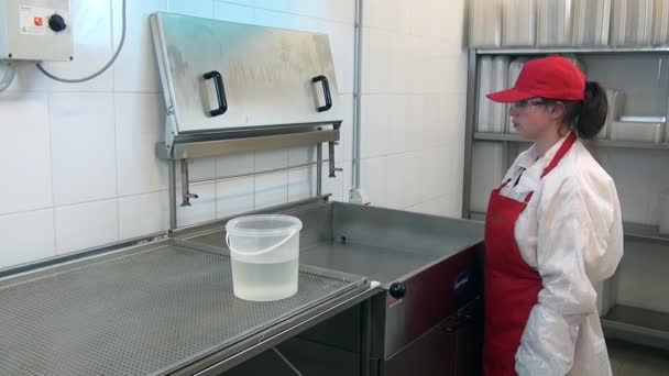 Woman in red apron and cap washes industrial deep fryer in workshop. — Stock Video