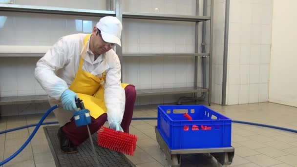 Arbeiter wäscht und desinfiziert rote Bürsten in Industriehalle. — Stockvideo