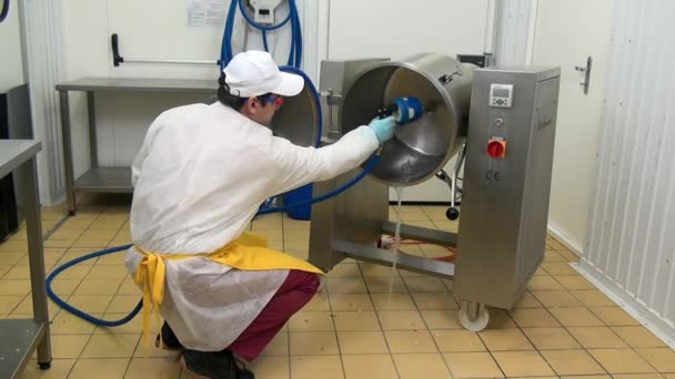 Man werknemer wast en desinfecteert industriële apparatuur voor het mengen van salade. — Stockvideo