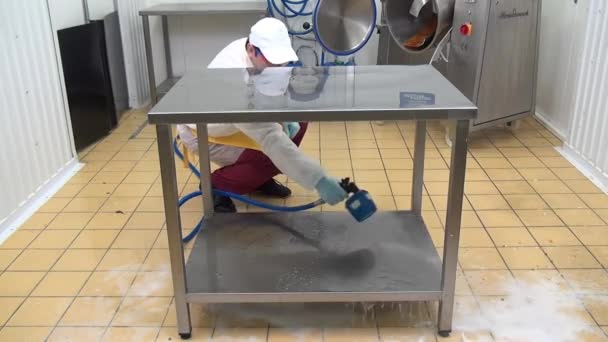 Robotnik zajmujący się produkcją żywności myje i dezynfekuje stół w warsztacie przemysłowym. — Wideo stockowe