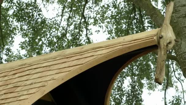 Ξύλινη κορυφή της οροφής του ξύλινου ιδιωτικού σπιτιού κοντά στο δέντρο την άνοιξη φεστιβάλ RHS Malvern Hills. — Αρχείο Βίντεο