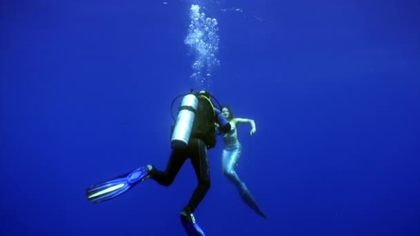 Ung kvinna sjöjungfru poser för kamera av kameraman under vattnet i havet. — Stockvideo