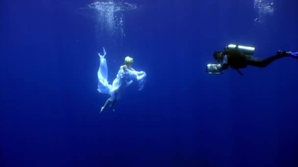Ange jeune femme modèle sous-marin en tissu blanc et caméraman. — Video