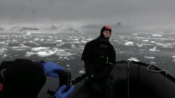 Oameni în barcă de cauciuc lângă floarea de gheață și aisbergul oceanului Antarctica . — Videoclip de stoc