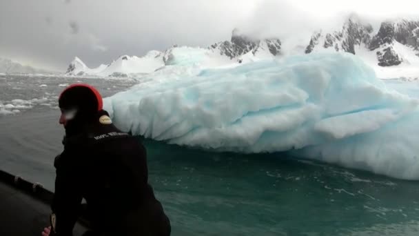 Menschen in Schlauchboot nahe Eisscholle und Eisberg des antarktischen Ozeans. — Stockvideo