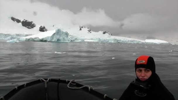 Ludzie w gumowej łodzi w pobliżu koperty lodowej i góry lodowej oceanu Antarktyda. — Wideo stockowe