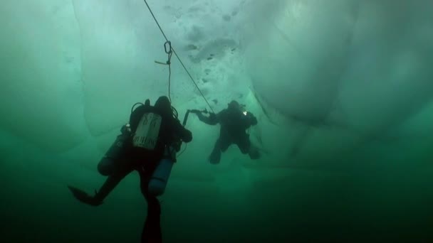 Unterwasserkameramann mit Kamera und Taucher unter dem Eis des Baikalsees. — Stockvideo