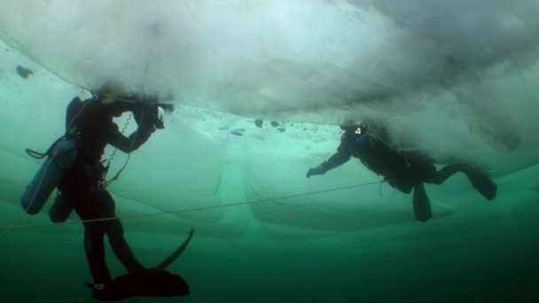 Υποβρύχια κάμεραμαν με κάμερα και τεχνικό δύτη κάτω από τον πάγο της λίμνης Baikal. — Αρχείο Βίντεο