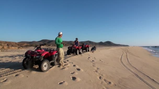 Grupa turystów na quad bike przejażdżka ATV na piasku i falujące powitanie. — Wideo stockowe