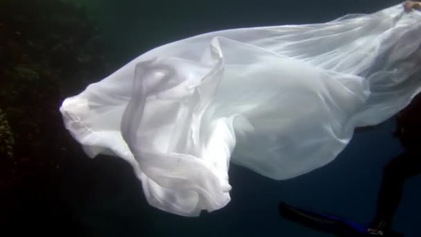 Jeune femme modèle sous-marin en tissu blanc sur fond d'eau bleue. — Video