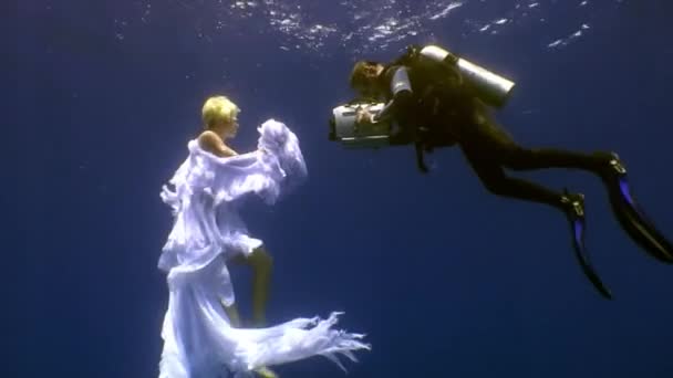 Jonge vrouw onderwater model engel in wit doek en cameraman. — Stockvideo