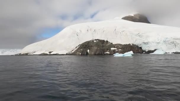 Ice cap dækker et bjerg med udsigt over et hav. – Stock-video