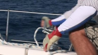 Erkekler yelkenli yatta halat vinç büküyor..