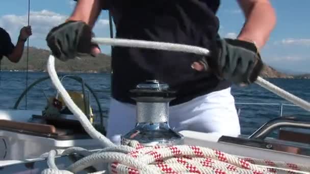 Kvinnen trekker tau om vinsj på en seilbåt i fart. – stockvideo