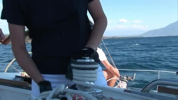 Женщина тянет верёвку на лебедке на движущейся парусной яхте. — стоковое видео
