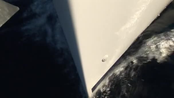 Le nez et les côtés du yacht blanc en mouvement coupe les vagues de surface de l'eau. — Video