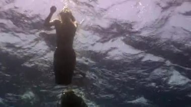 Kameraman su altında genç bir kadını görüntülüyor..