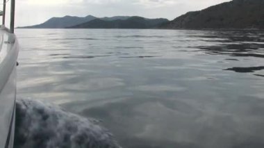 Hareket halindeki beyaz yat, su yüzeyinin dalgalarını kesiyor..