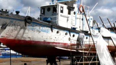 İşçiler tersanede tamirat sürecinde metali boyayla parçalıyorlar..