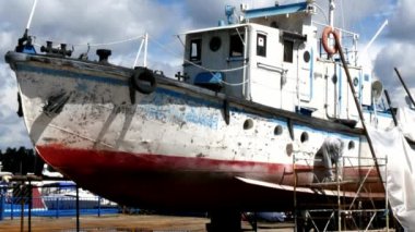 İşçiler tersanede tamirat sürecinde metali boyayla parçalıyorlar..