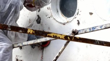 İşçiler tersanede tamirat sürecinde metali boyayla parçalıyorlar..