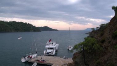 Körfezdeki rıhtımın yanında duran beyaz yatta insanlar var..