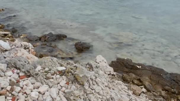 Čistě průhledný vodní povrch lehkých vln a skal na mořském pobřeží. — Stock video