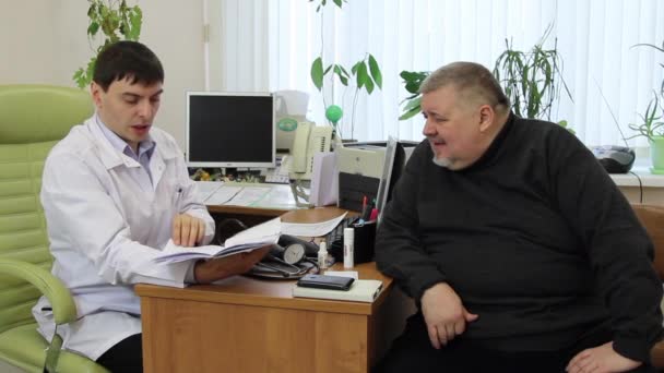 Medico in un camice bianco consulta il paziente grasso uomo in clinica . — Video Stock