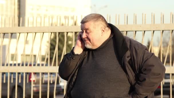 A fat man talking on the phone and very nervous on city street. — Stock Video